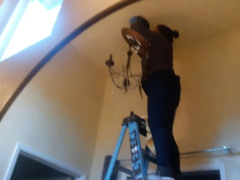 Electrician installing a chandelier in a Center Line residence